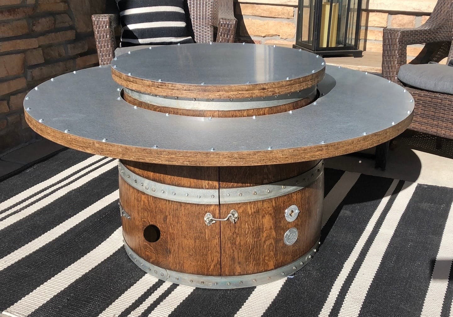 Coffee table height barrel fire pit with its ring top and center lid on a striped rug