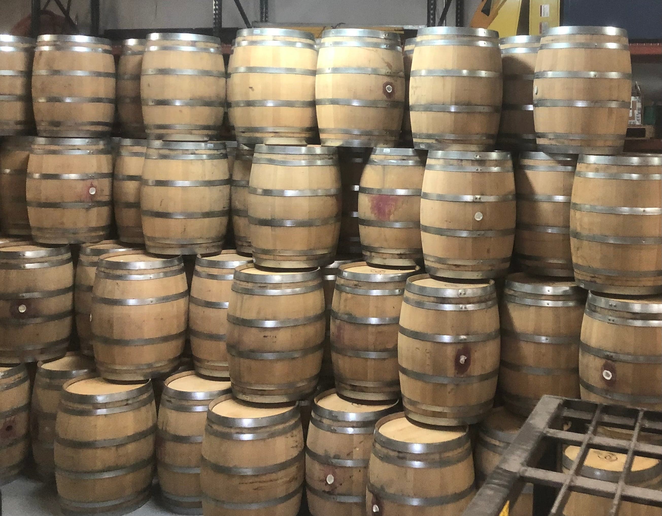 Stacks of oak wine barrels with metal hoops in the Wine Barrel Dude shop