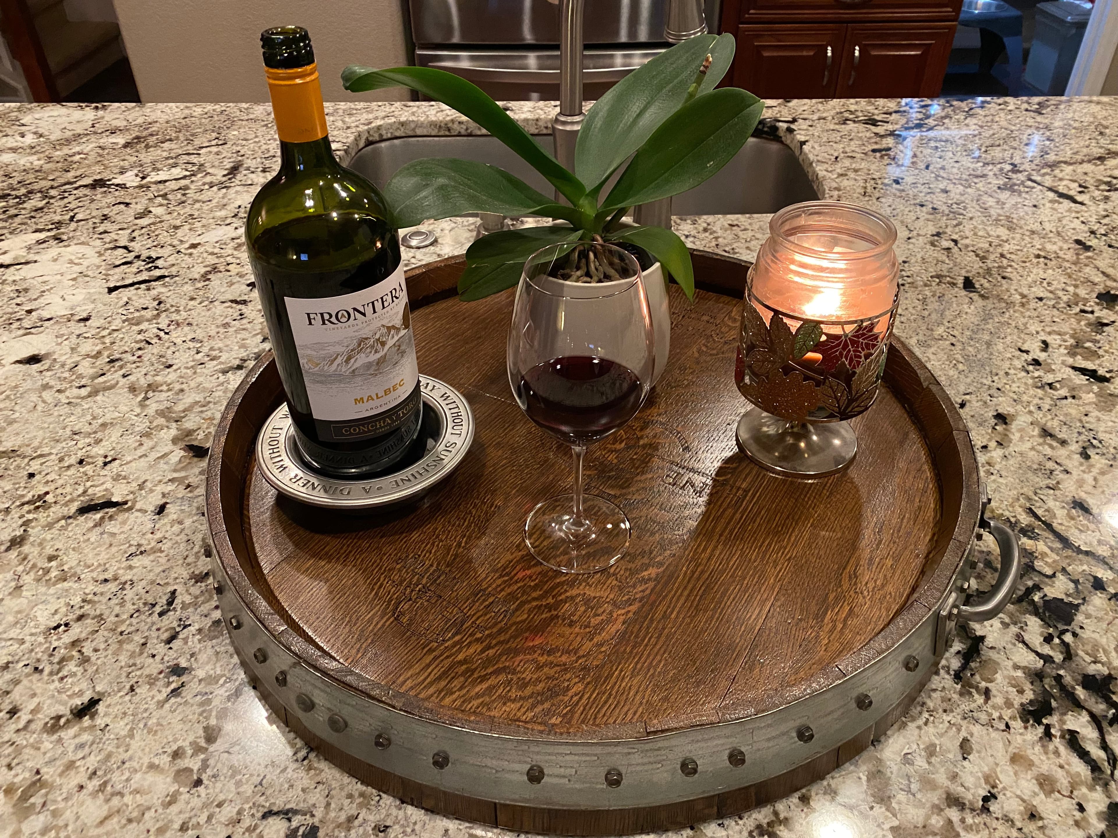 Barrel head serving tray with a wine bottle, a glass of red wine and a candle
