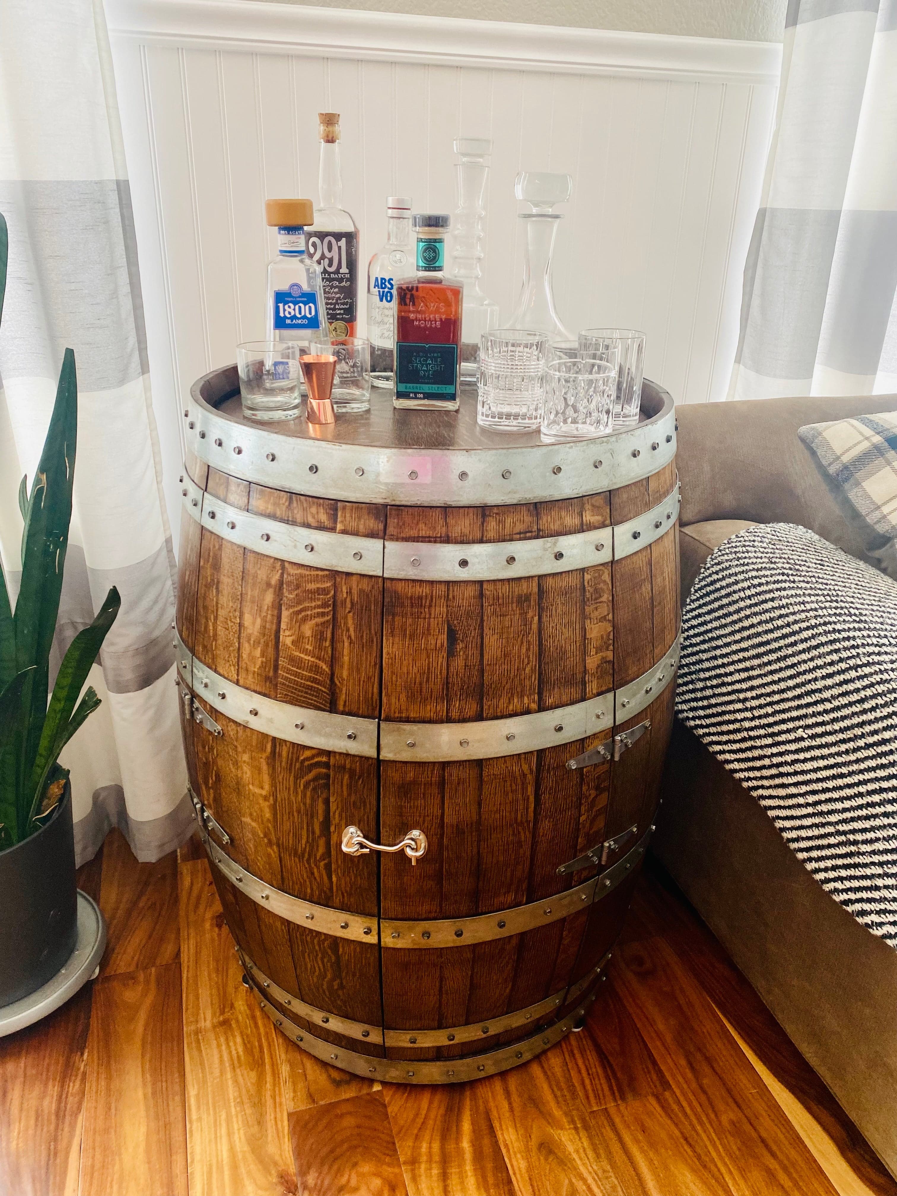 Upright oak barrel used as a home bar with bottles and glasses on top