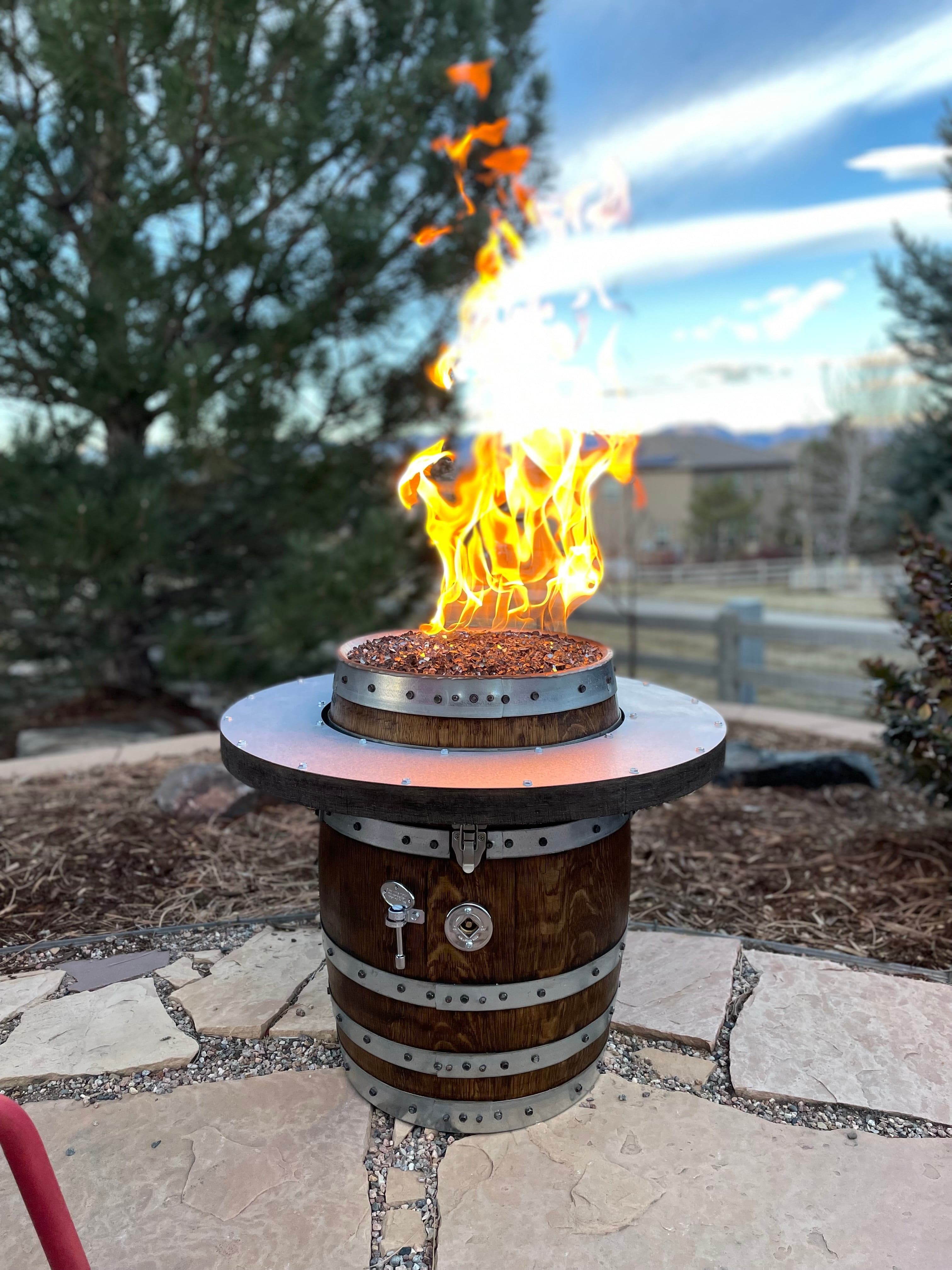 Small whiskey barrel fire pit with a ring tabletop and flame on a flagstone patio