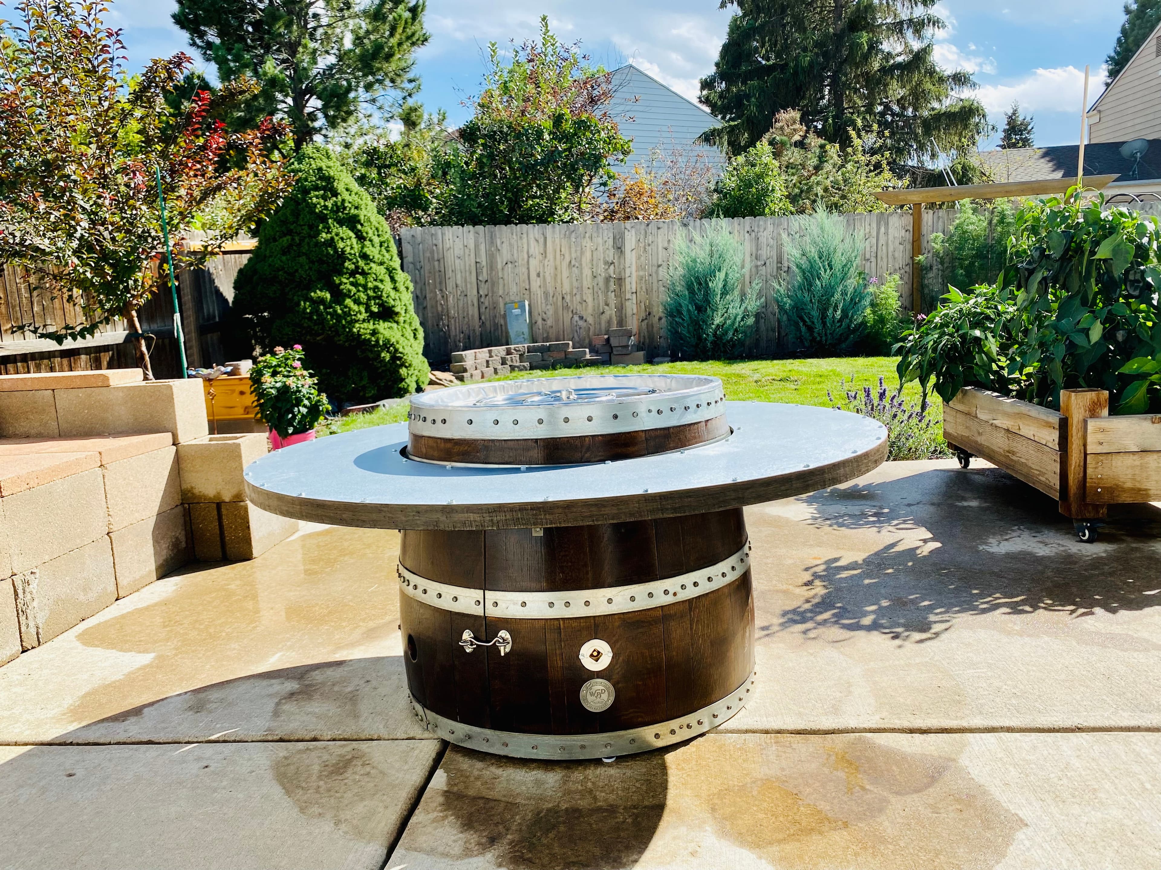 Barrel fire pit with a wide ring tabletop on a sunny backyard patio